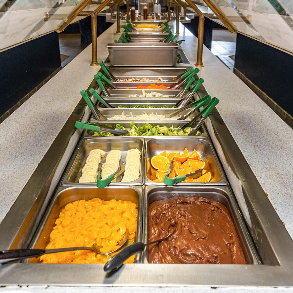 A long buffet line at Hi Ho Mongolian Grill with various fresh ingredients and desserts.