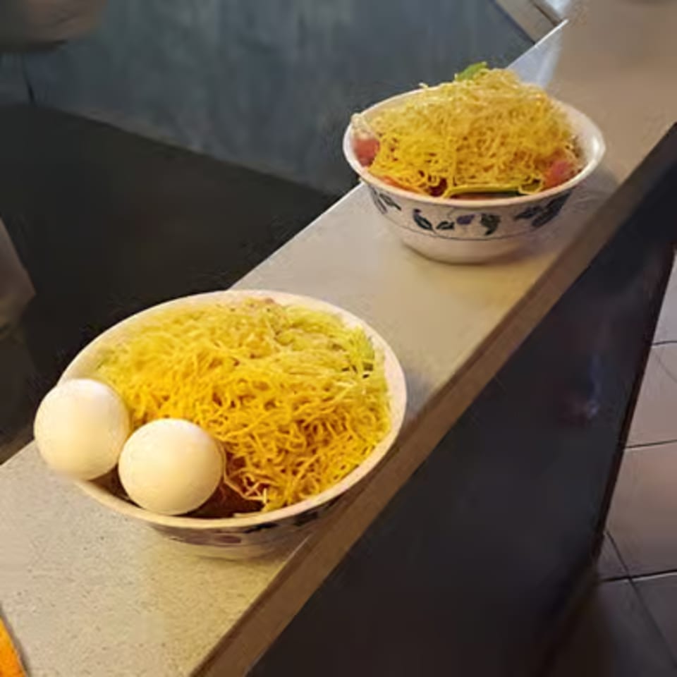 Two bowls of noodles with eggs and other ingredients, ready for cooking at Hi Ho Mongolian Grill.