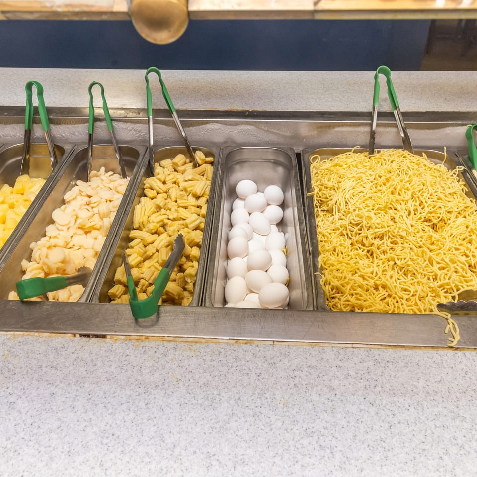 Buffet bar with noodles, baby corn, water chestnuts, pineapple, and hard-boiled eggs at Hi Ho Mongolian Grill.