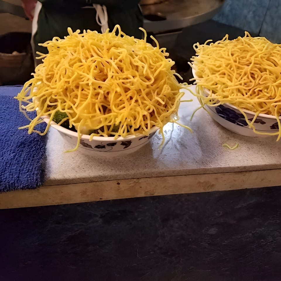 Two bowls overflowing with crispy chow mein noodles on a counter at Hi Ho Mongolian Grill.